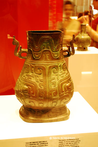 Vas de bronz decorat cu chipuri de animale. Vas pentru vin cu destinatie rituala. Manerele sunt in forma de elefant, devenit motivul decorativ al dinastiei Shang. Este datat in perioada tarzie a dinastiei Zhu (IX-771 i.Ch.)